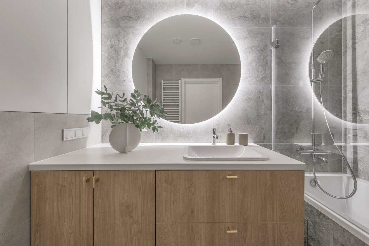 Modern vanity with round backlit mirror and stone tile